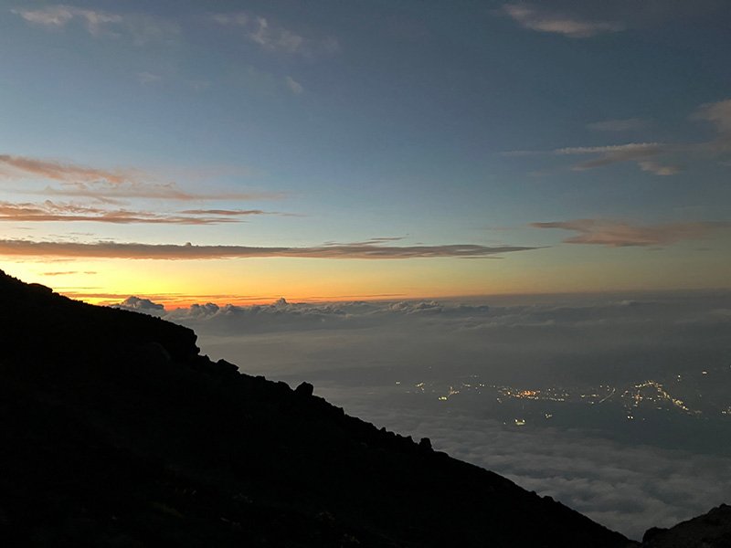 山小屋から見た夕焼けと街明かりの写真